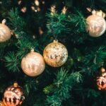 Festive holiday ornaments including gold and copper colors adorning a Christmas tree.