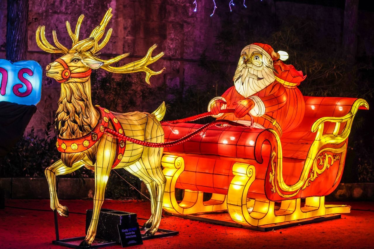 Brightly illuminated Santa sleigh display at a festive night event, perfect for holiday themes.